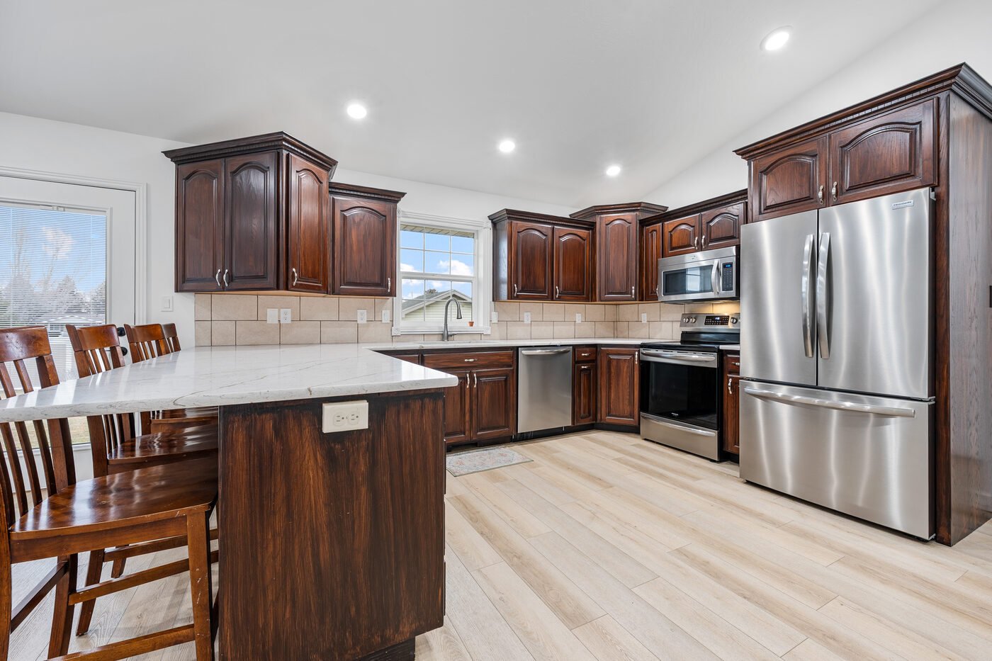 Updated kitchen with dark wood cabinets, quartz countertops, island with bar seating, and stainless appliances at 625 Vale Lane Rexburg Idaho